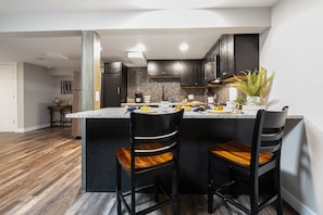 A modern kitchen with dark wood cabinets, a central island with bar stools, and a stone backsplash.