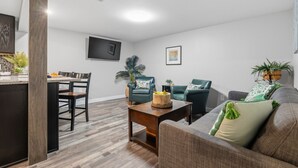 A modern living room with a sofa, two armchairs, a coffee table, and a dining area with a table and chairs. - Modern Reynoldsburg Retreat Near Columbus (Reynoldsburg)