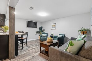 Un salon moderne comprenant un canapé, deux fauteuils, une table basse et un coin repas avec une table et des chaises.