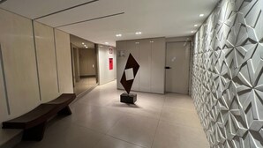 Ein moderner Flur mit einer Bank, einer geometrischen Skulptur und einer Wand mit Muster.