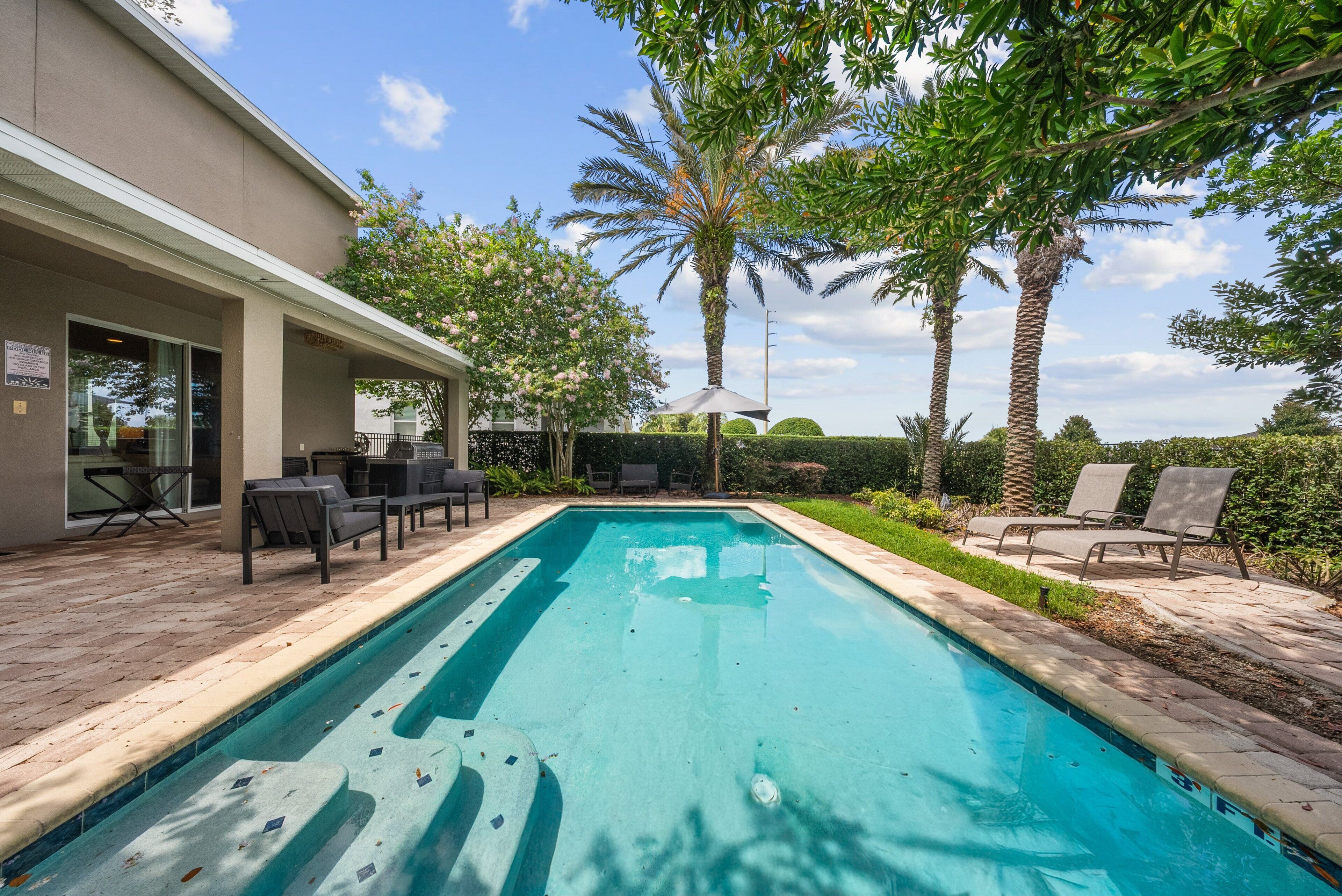 A swimming pool with lounge chairs and a covered patio area.