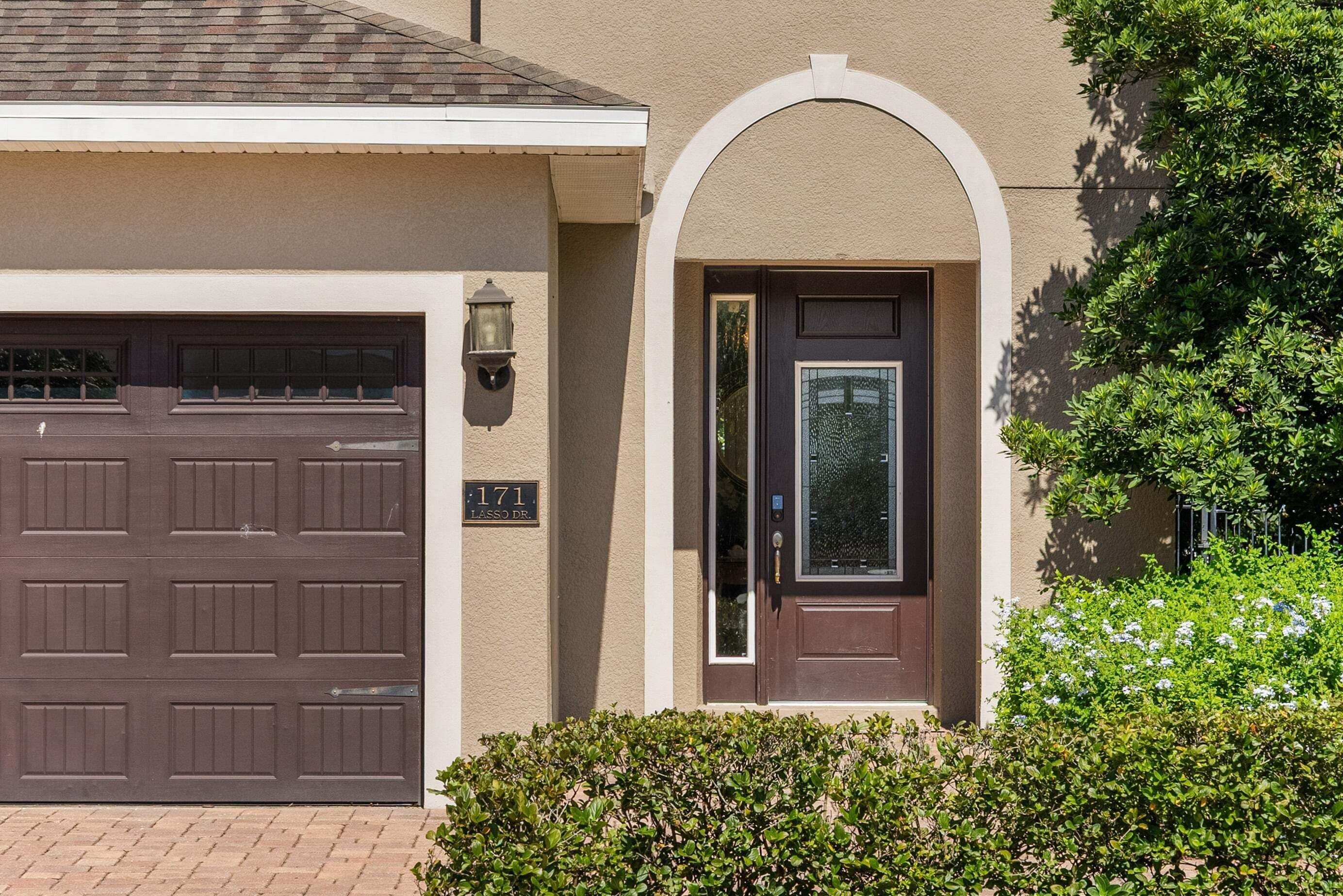 A residential house with a garage door, a front door with a glass panel, and a mailbox.