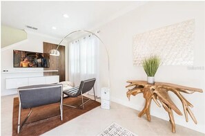 Ein modernes Wohnzimmer mit Sofa, Sesseln, Couchtisch, Fernseher und einem einzigartigen Holznachttisch.