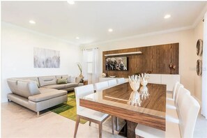 Ein modernes Wohnzimmer mit einer Eckcouch, einem Esstisch mit Stühlen, einer Holzvertäfelung und einem Wandbild.