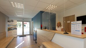 A reception area with a wooden counter, a glass partition, and a signboard.
