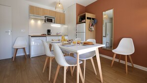 A modern kitchen with white appliances, wooden cabinets, and a dining area with white chairs and a table.