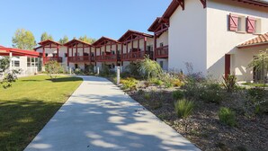 A building with multiple balconies, a paved walkway, and a landscaped garden.