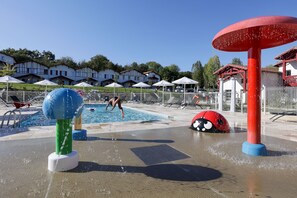 En vattenpark med en pool, vattenlekredskap och parasoller.