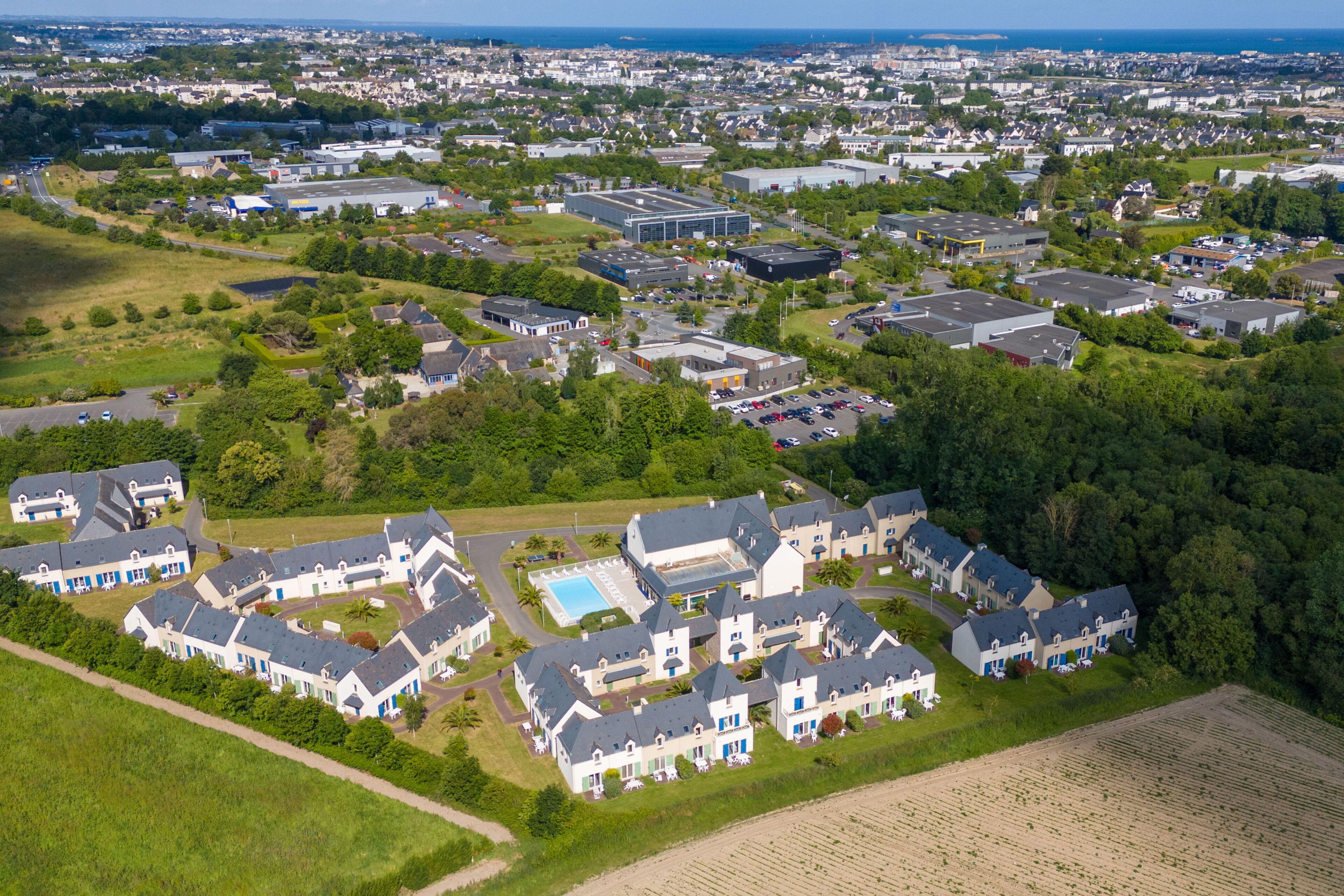 An aerial view of a residential area with houses, a swimming pool, and a large building complex.