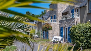 A residential building with a stone facade, balconies, and outdoor seating.
