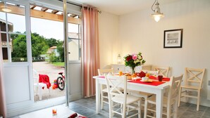A dining area with a table set for four, a window with curtains, and a view of the outside.