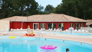 A swimming pool with lounge chairs and a building with a red facade in the background.