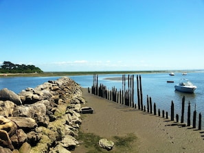 A rocky shoreline with a row of wooden posts, calm water, and boats. - À 10 min à pied de la plage | 2 Piscines sur place (Arès)