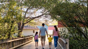 Uma ponte de madeira com uma família caminhando.