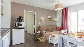 A compact living space with a kitchenette, a dining area, and a sofa.
