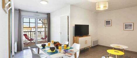 A modern dining area with a table, chairs, and a television.