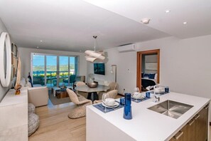 Eine moderne Küche mit Kochinsel, Essbereich mit Stühlen und einem großen Fenster mit Ausblick.