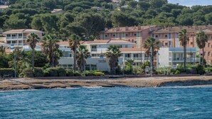 Ein Küstenhotel mit mehreren Gebäuden, Palmen und einem Strand im Vordergrund.