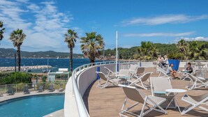 Ein Poolbereich mit Liegestühlen, einem Pool und Blick auf das Meer und die Hügel.