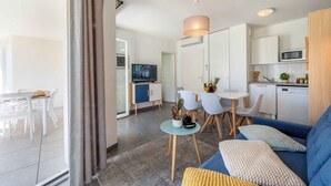 Ein modernes Wohnzimmer mit einer Couch, einem Esstisch, Stühlen und einem Fernseher.