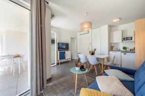 Ein modernes Wohnzimmer mit einer Couch, einem Esstisch, Stühlen und einem Fernseher.