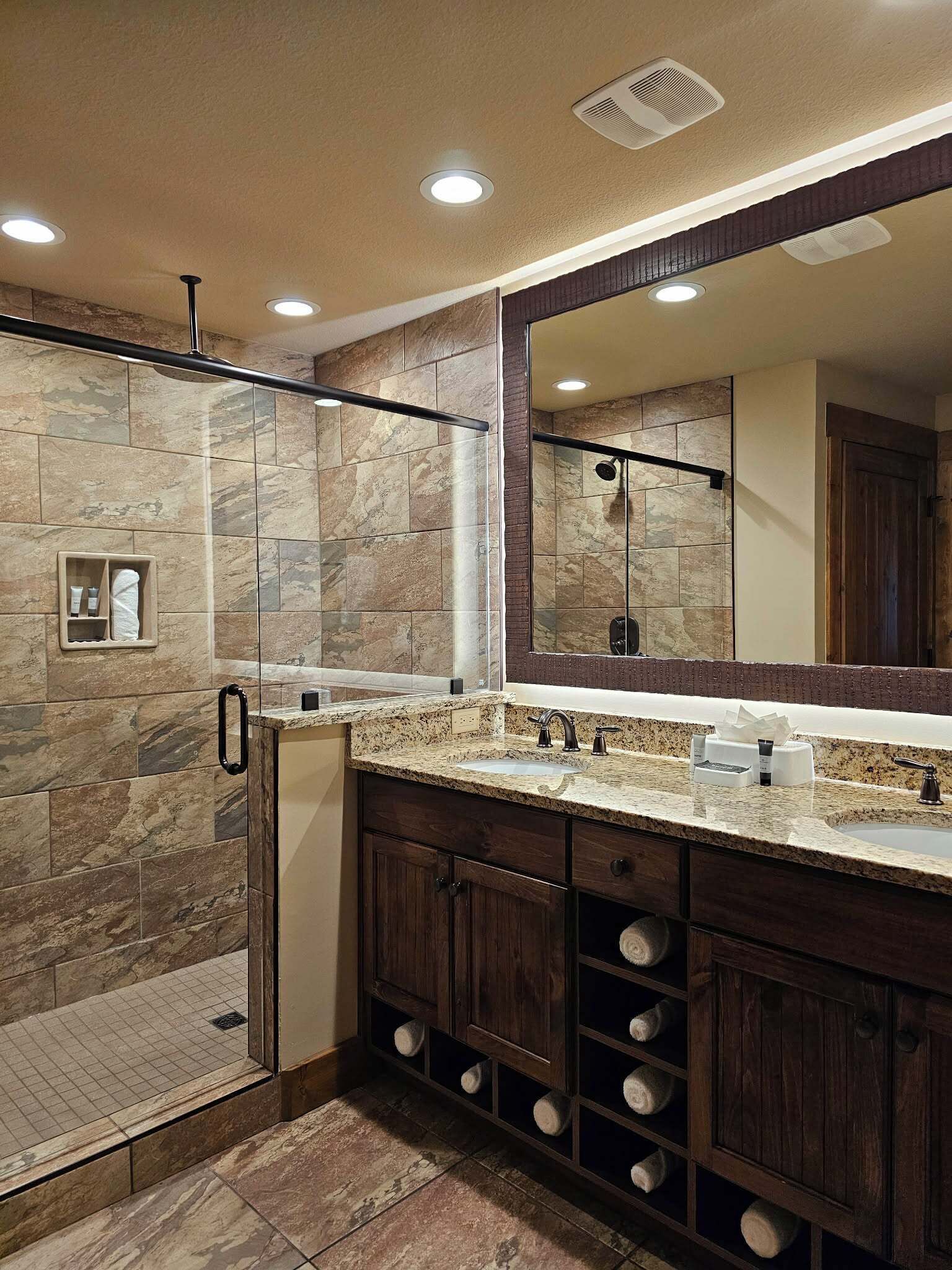 Un bagno con doccia, uno specchio grande, un lavabo e cassetti contenitori.