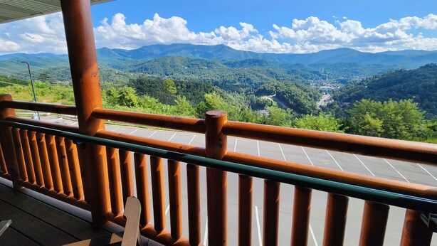 Un balcón de madera con vista a un valle y montañas.