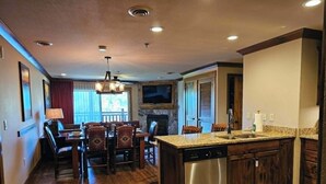 Una cocina moderna con una isla central, lavavajillas integrado y un comedor con sillas y mesa de madera.