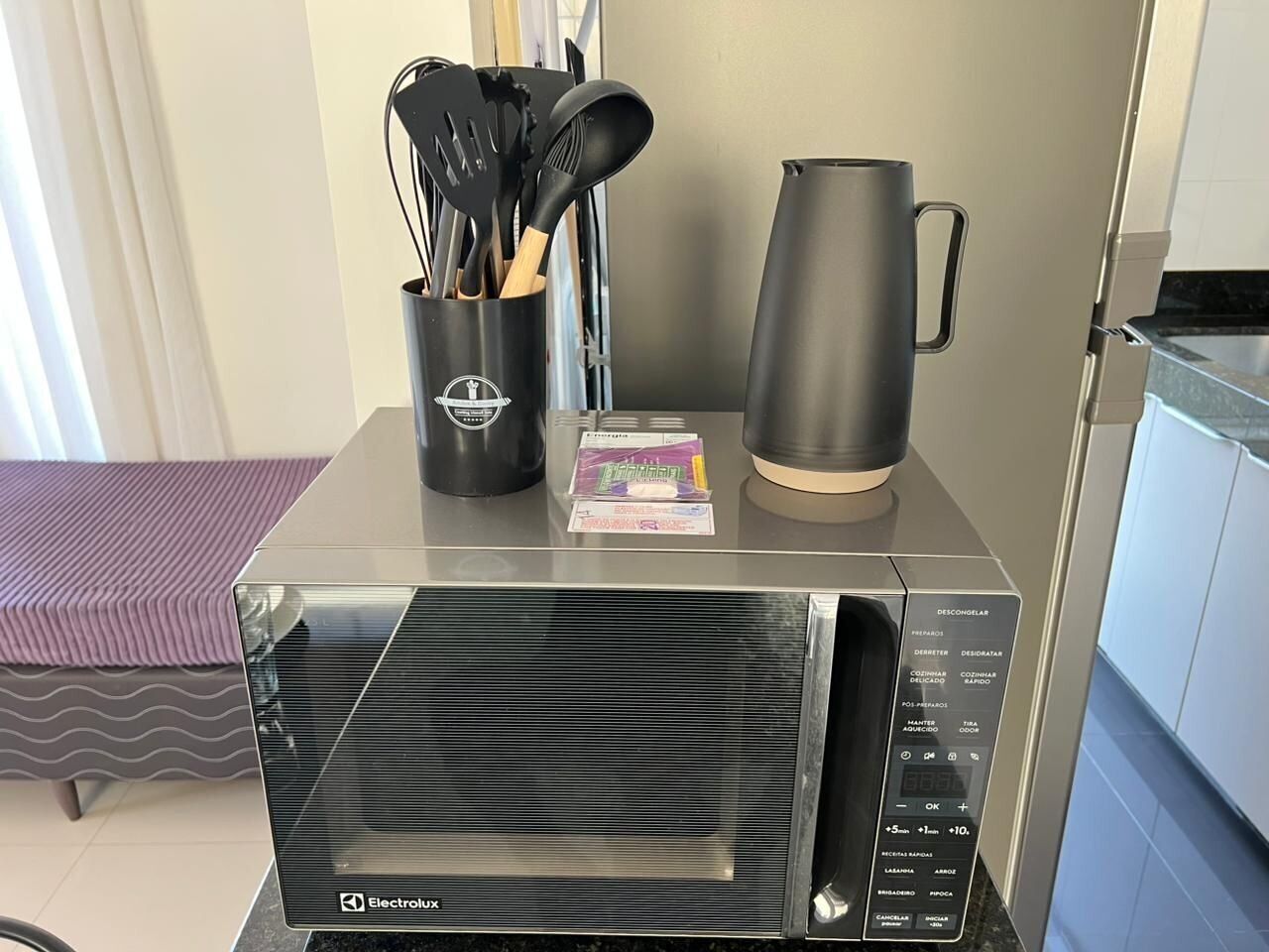Una cocina compacta con microondas, cafetera y un portavasos.