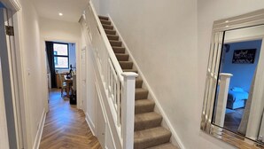 Eine Treppe mit Teppichstufen und weißen Geländern, die zu einer oberen Etage führt.