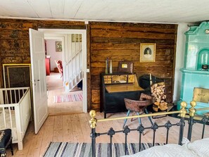 Une pièce avec un plancher en bois, un lit avec un cadre en métal, un bureau avec une chaise, un escalier et une armoire bleue.