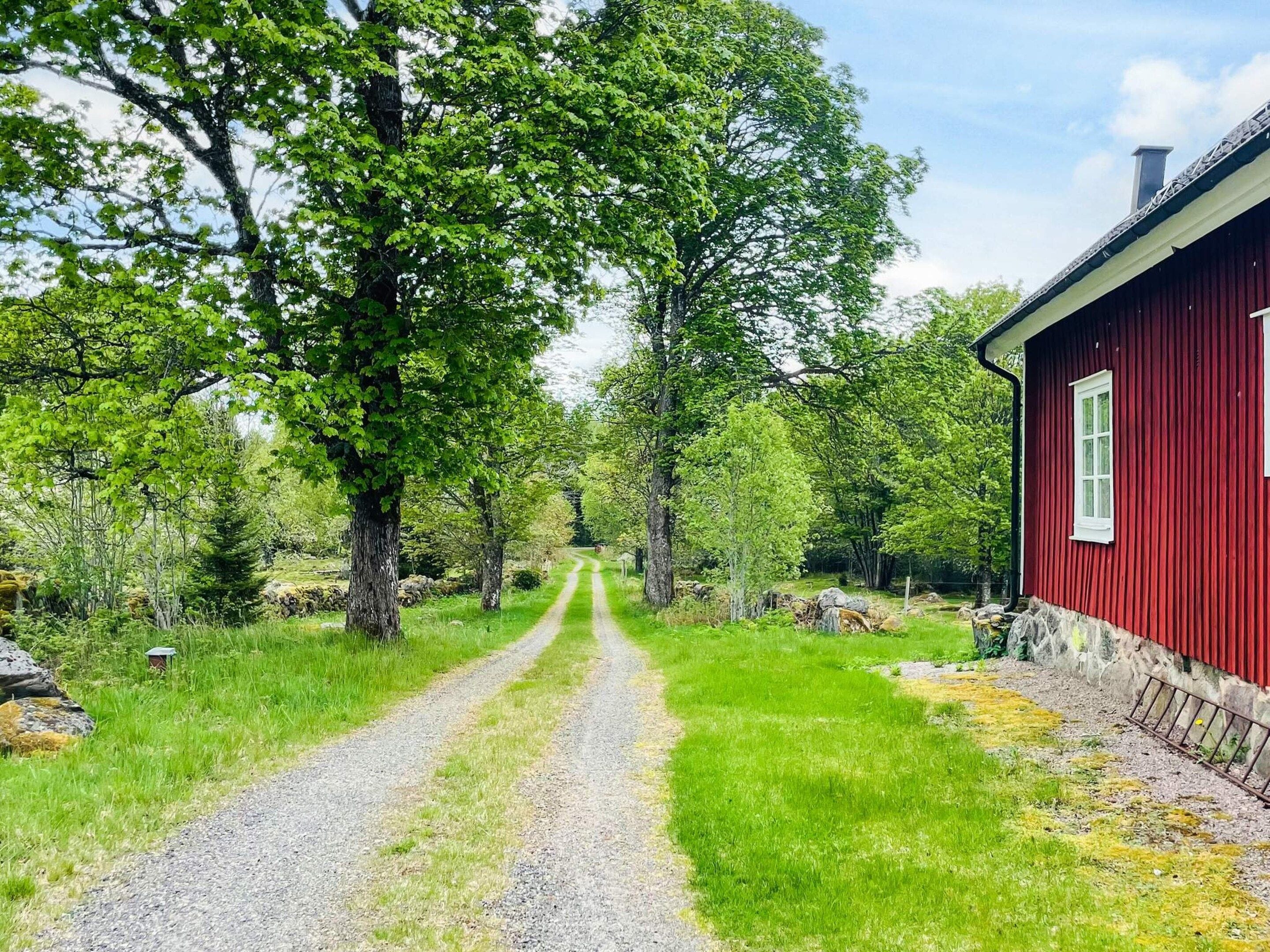 A gravel path leading to a red building surrounded by trees.