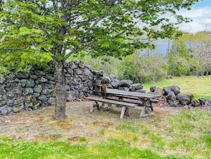 Eine Steinsäule, ein Holztisch und ein Baum in einer natürlichen Umgebung.