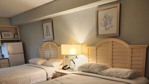 Une chambre d’hôtel avec deux lits, une table de chevet avec une lampe, un téléphone et un four à micro-ondes posé sur un meuble.