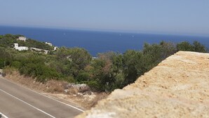 Una carretera costera con vistas despejadas al mar y edificios a lo lejos.