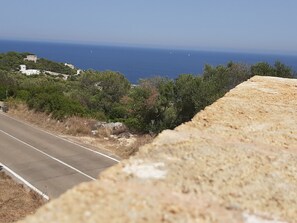 Eine Küstenstraße mit freiem Blick auf das Meer und entfernte Gebäude.