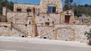 Un edificio de piedra con una escalera, un balcón lleno de flores y una ventana.