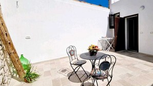 Un patio con una mesa, sillas, una botella verde y una planta en maceta.