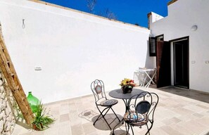 Eine Terrasse mit Tisch und Stühlen, einer grünen Flasche und einem Blumentopf.
