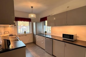 A kitchen with a microwave, cabinets, and a window with curtains. - Large Holiday Home With Private Garden (Choczewo)