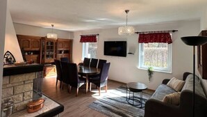 A living room with a fireplace, dining area, and a sofa. - Large Holiday Home With Private Garden (Choczewo)