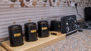 Una cocina con encimera de granito, un tostador y tres recipientes negros con detalles dorados.