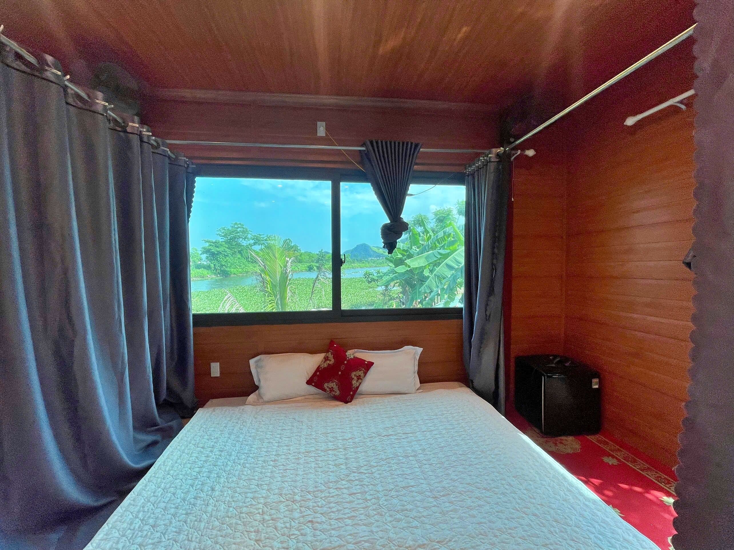 A room with a bed, curtains, a window, and a speaker.