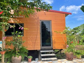 Ein Holzhaus mit rotem Dach, einer Glastür und einer kleinen Treppe zum Eingang.