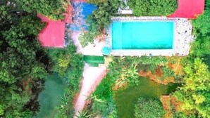 An aerial view of a property with a swimming pool, surrounded by greenery and a small pond. - Hideaway Village Homestay (Hoa Lu)