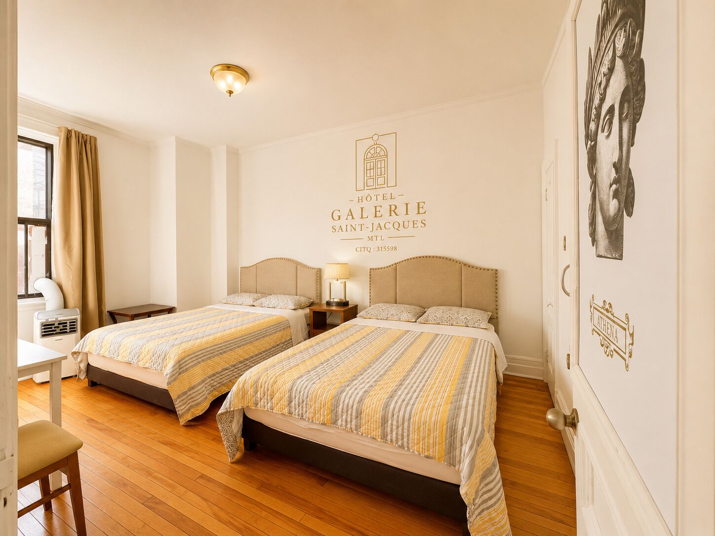 A hotel room with two beds, a desk, and a window with curtains.