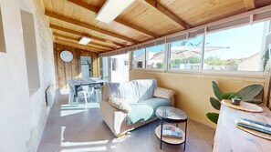 Ein gemütliches Zimmer mit Holzbalkendecke, einer Couch, einem kleinen Tisch und einem Fenster mit Blick nach draußen.