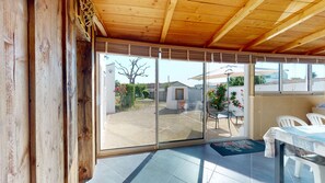 Eine überdachte Terrasse mit Blick auf einen Garten und einem weißen Stuhl.
