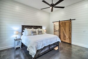 Ein Schlafzimmer mit Bett, Nachttischen, Deckenventilator und Holztür.