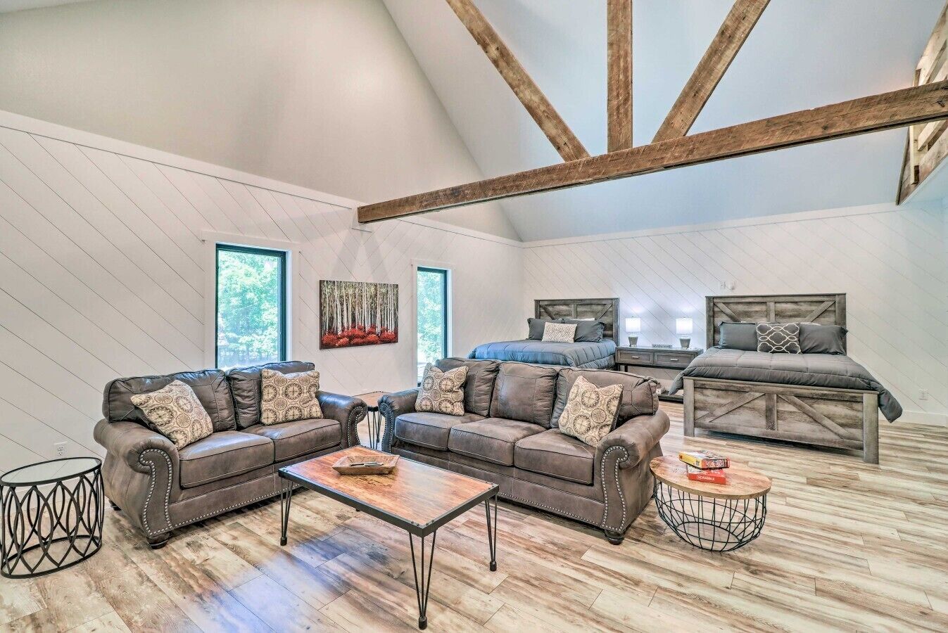 Une chambre spacieuse de style loft, avec un lit en mezzanine, deux canapés en cuir, une table basse et une grande fenêtre.
